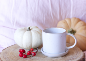 a cozy scene with a coffee mug and pumpkins